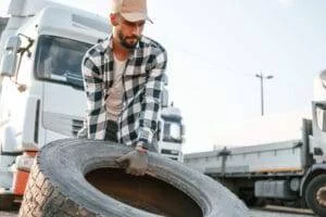 With broken tire. Young truck driver is with his vehicle at daytime